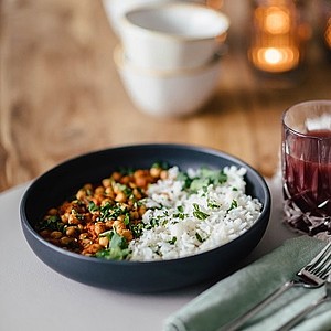 Kichererbsen-Curry mit Reis an einem gedeckten Tisch